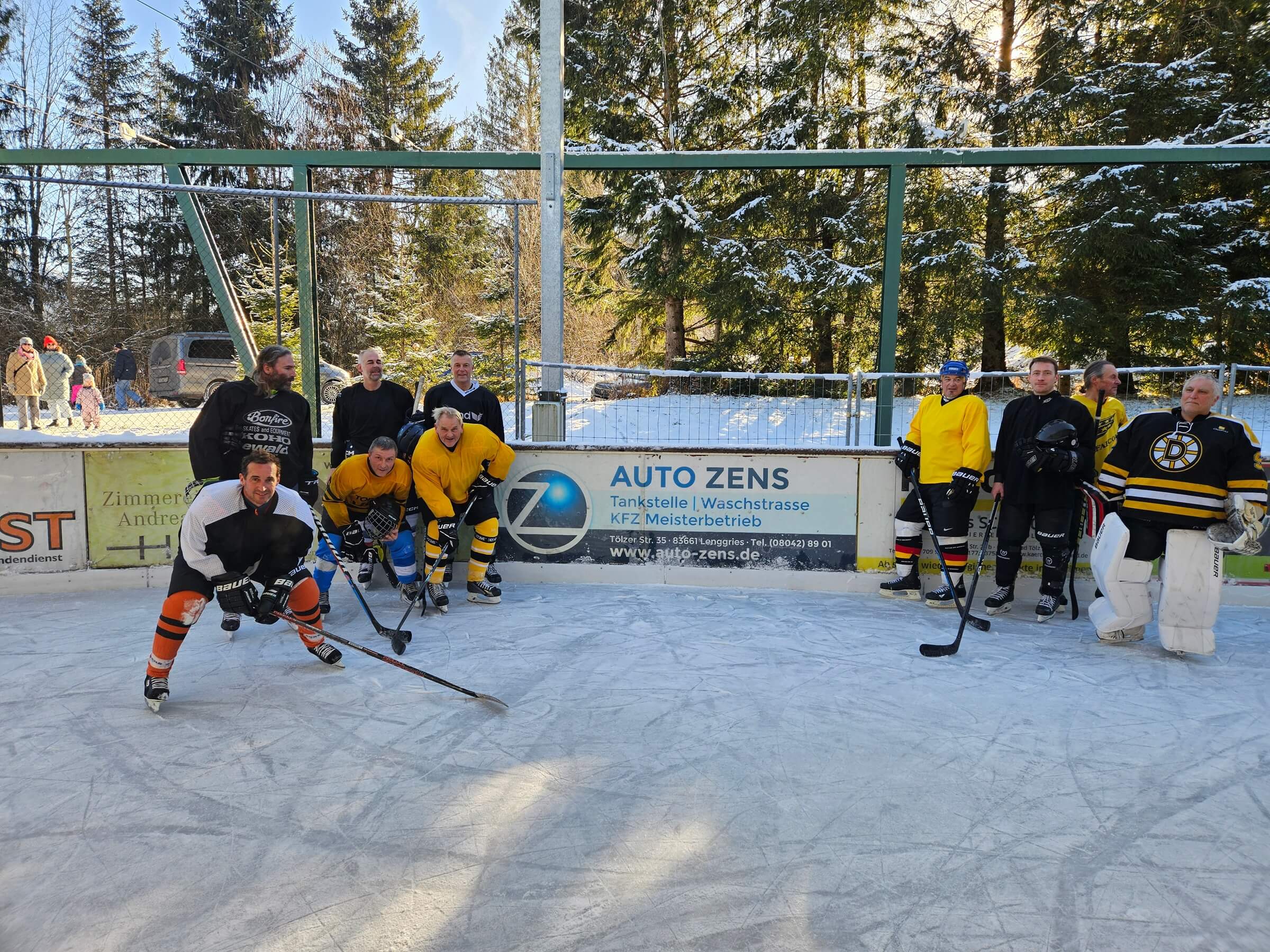 Bild: Eishockeyspieler auf einer Outdoor-Eisbahn vor Werbebanden im Winter, bereit für das Spiel.